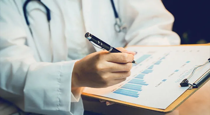A medical professiona reviewing and signing medical reports related to healthcare.